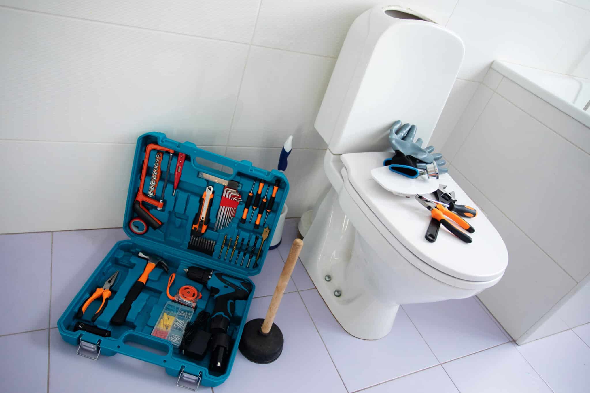 WC avec une boîte à outils bleu avec différents outils à l'intérieur.